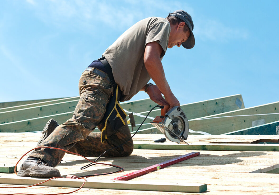 Professional roof installation—contractor cutting roof decking with a circular saw.
